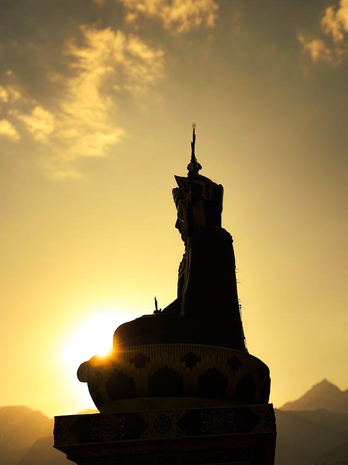 A captivating silhouette of a Buddha statue against the sunset in HP, India, highlighting its spiritual and architectural significance.
